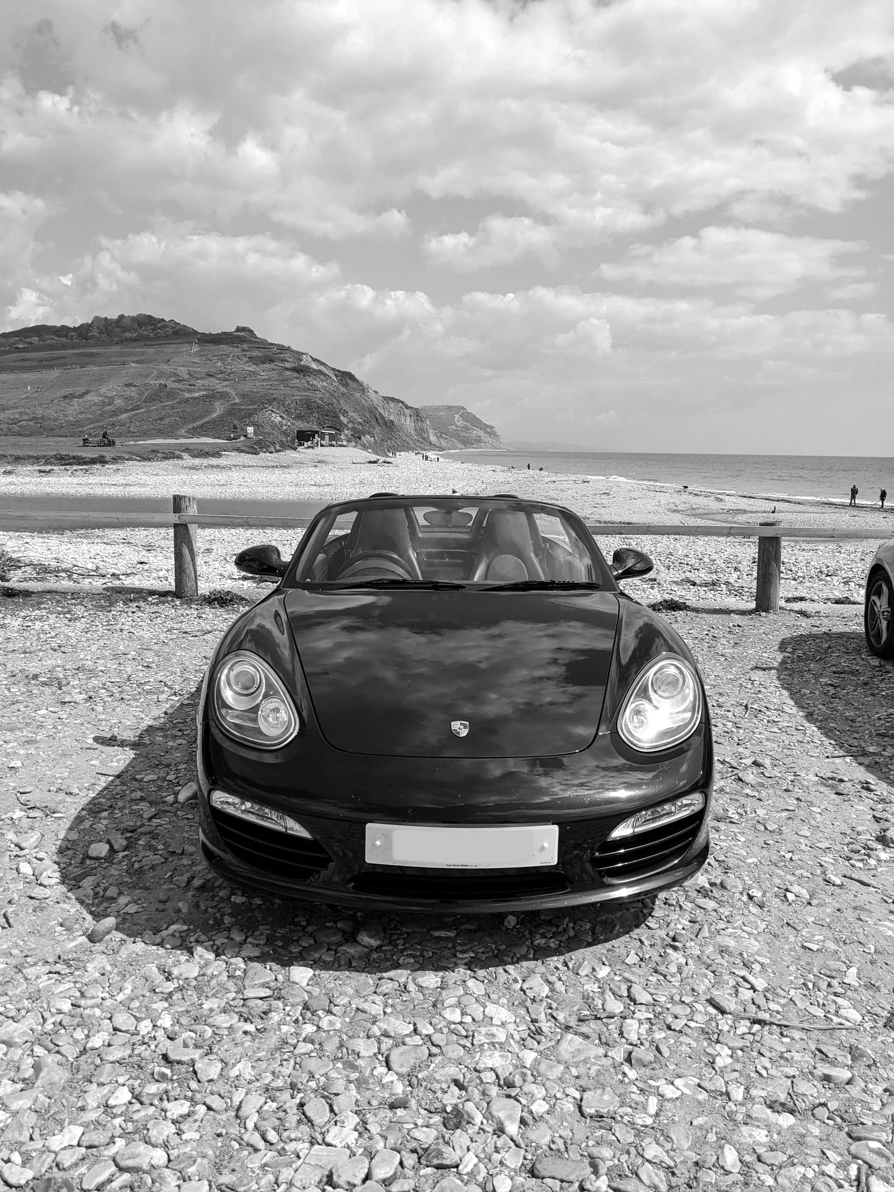 A Boxster at the beach car park in Charmouth, the cliffs behind
